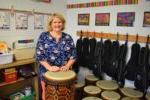music teacher behind a drum with drums and ukuleles behind her